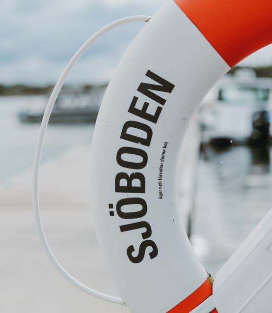 En boj i rött och vitt. skärgård och sommar. Sjöboden skärgårdskrog. Middag i skärgårdsmiljö intill havet. Mat och dryck i skärgårdsmiljö.